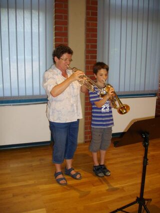 Musiklehrerin und Schüler spielen Trompete